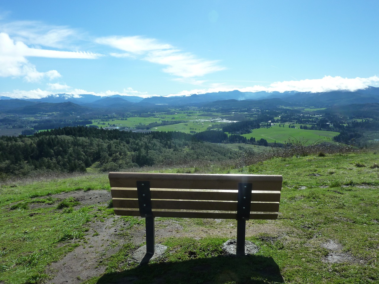 Wooden bench overlooks green mountain valley